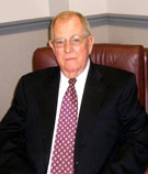 Ed Crenshaw, CIC at V.R. Williams and Company in Winchester, TN, wearing a black suit while sitting in a brown leather chair