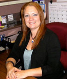 Heather Gifford, wearing a black jacket over a blue shirt, sits a brown desk at V.R. Williams and Company in Winchester, TN