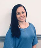 Katy Weber, pilot car account manager, wearing a blue shirt in front of a whiteboard at V.R. Williams and Company in Winchester, TN