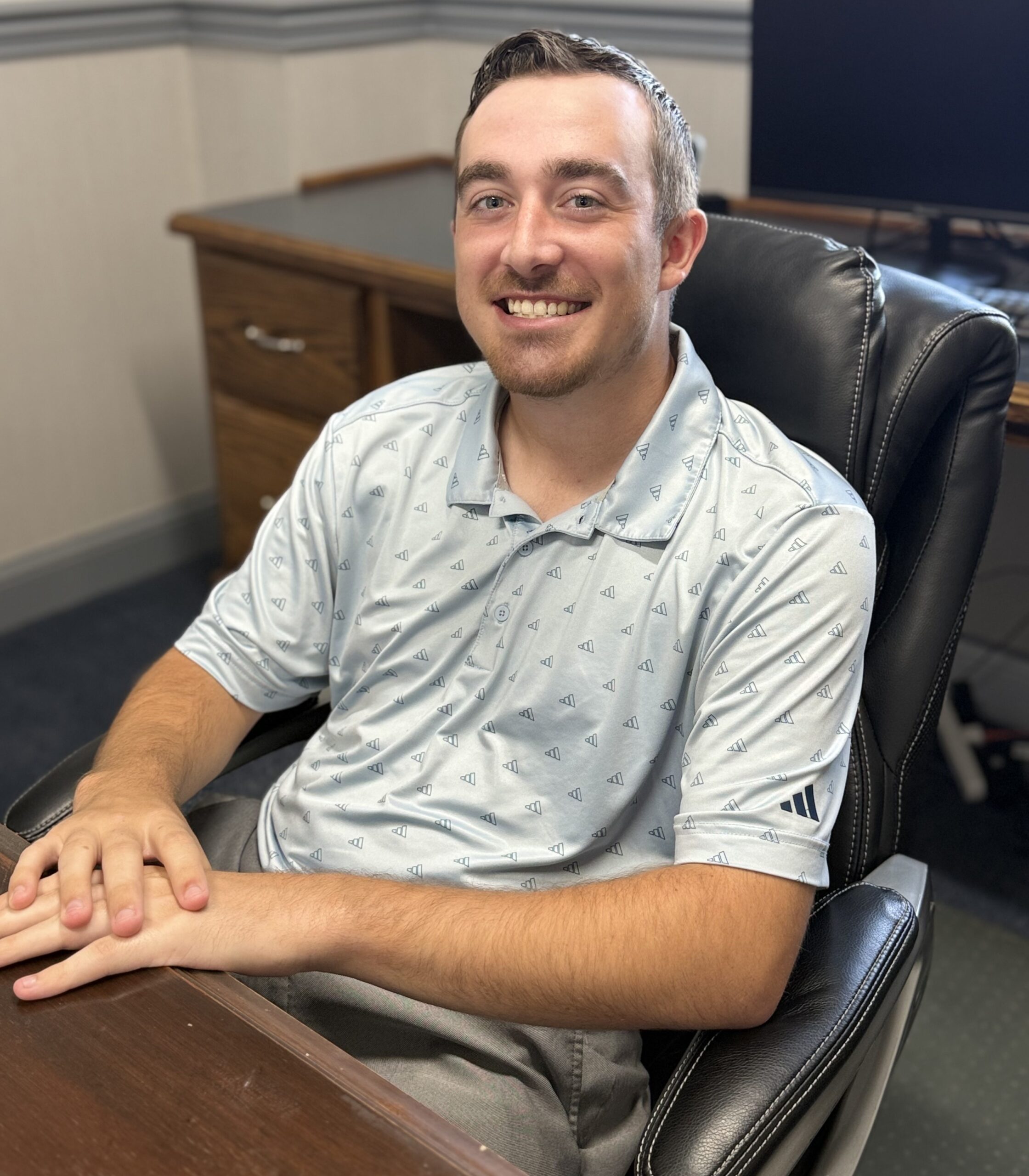Michael Greer, agribussines and farm insurance specialist at V.R. Williams and Company in Winchester, TN, wearing a blue shirt at a wooden brown desk